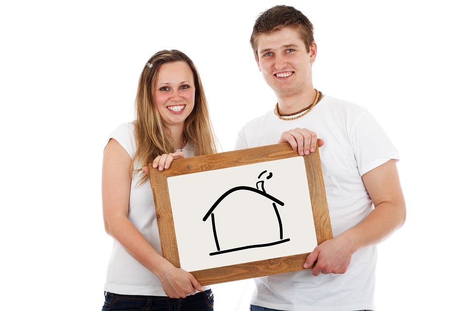 Young couple holding a drawing of a house