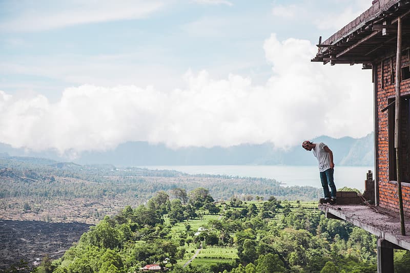 Man looking down from house on top of cliff