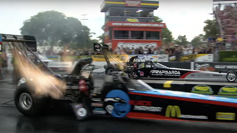 Top Fuel dragsters accelerate off the start line, burning rubber and fuel at a prodigious rate, bringing the cheers of the crowd. The burnt fuel and rubber may not be great for the environment, but it sure sounds and smells good. Screenshot of Youtube.