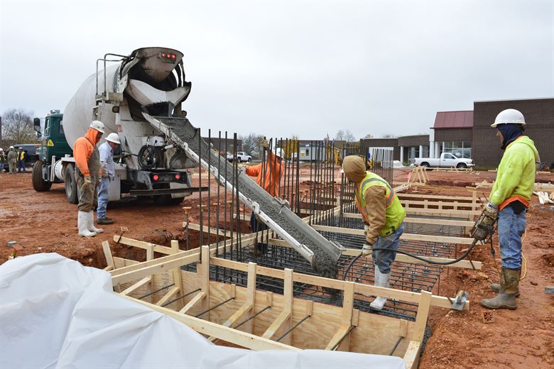 Builders pouring concrete at construction site