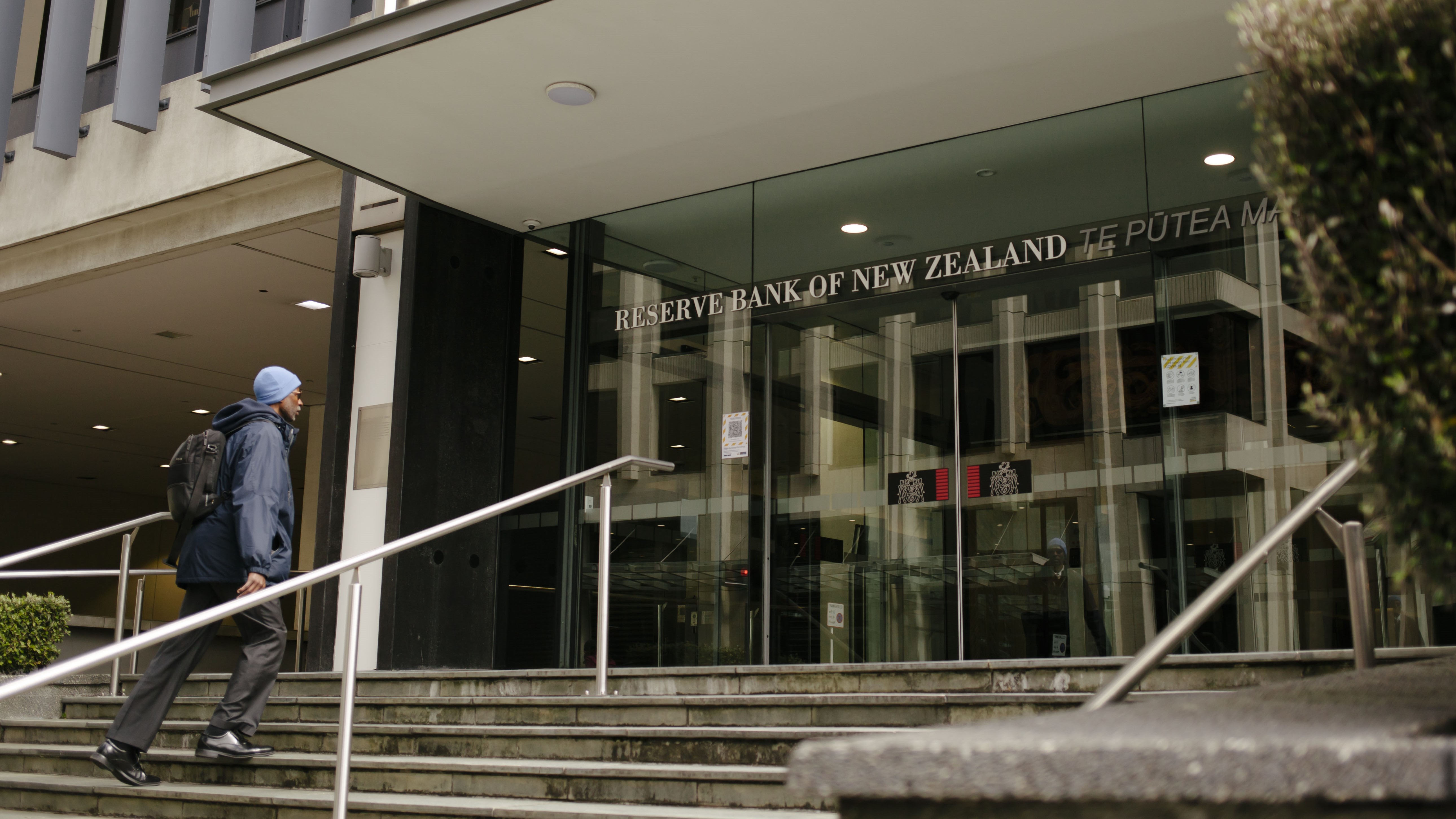 A man dressed in blue walks up the steps to the Reserve Bank of New Zealand. 