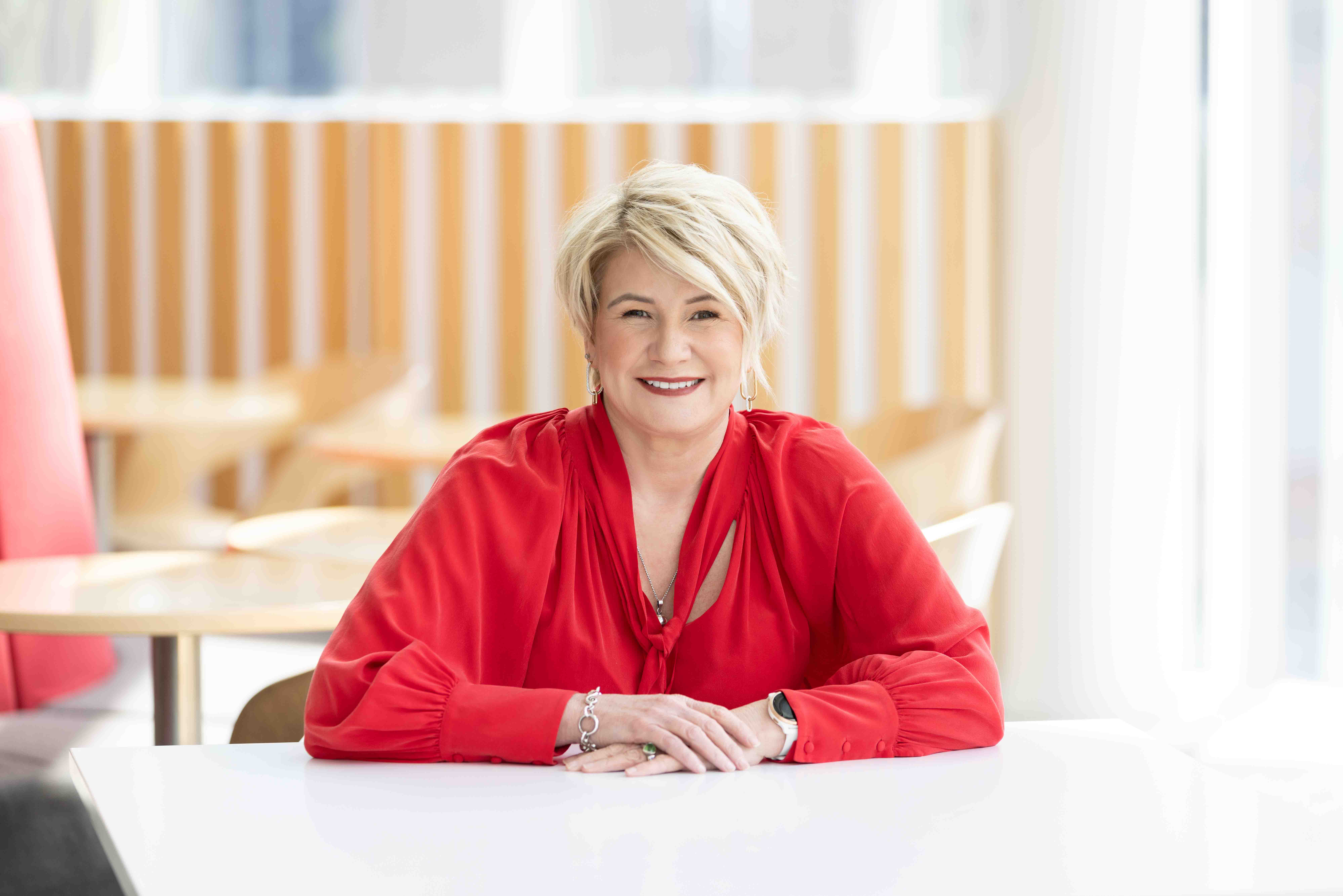 IAG New Zealand's chief executive Amanda Whiting sits at a table looking at the camera.