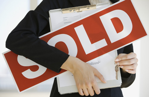Real estate agent holding sold sign