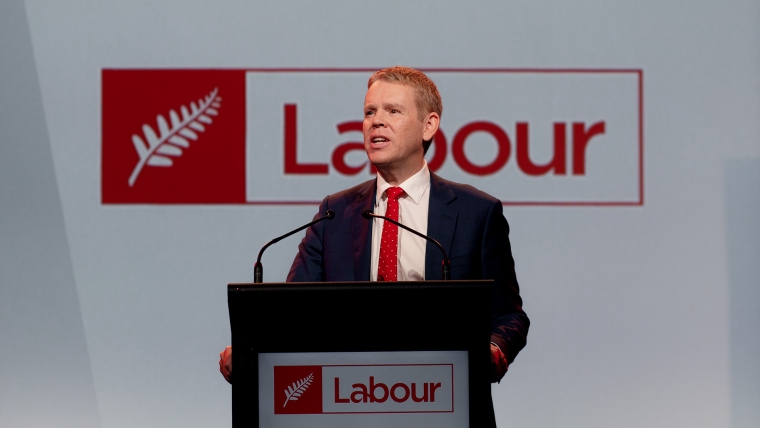 Prime Minister Chris Hipkins gives a speech in front of a Labour logo