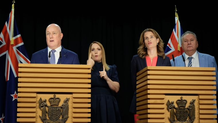 Prime Minister Christopher Luxon addresses reporters at a post-Cabinet media conference alongside a sign language interpreter, Finance Minister Nicola Willis and Associate Energy Minister Shane Jones.