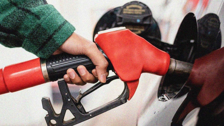 A hand holding a petrol pump. 
