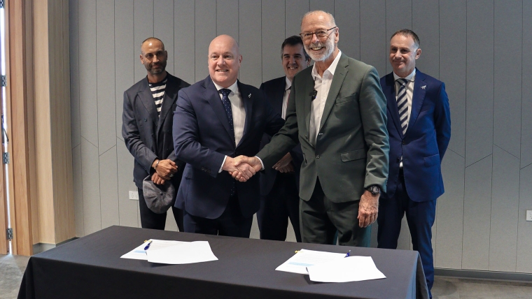 Prime Minister Christopher Luxon and Auckland Mayor Wayne Brown shake hands while Deputy Chair of Ngāti Whātua Ōrākei, Infrastructure Minister Chris Bishop and Auckland Minister Simon Watts smile in the background. 