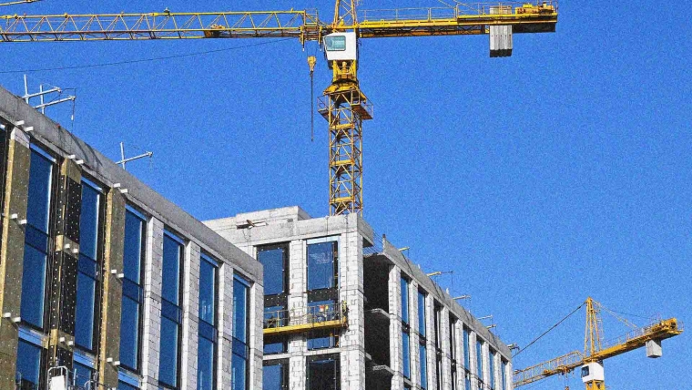 Crane and building under construction against blue sky.