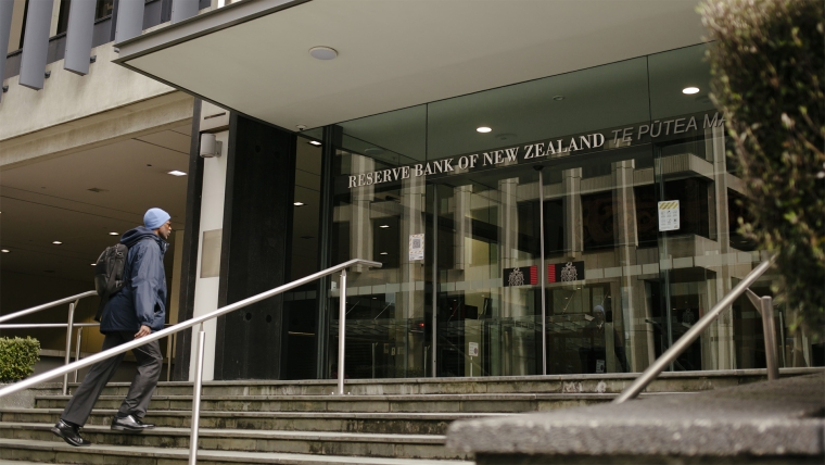 A man dressed in blue walks up the steps to the Reserve Bank of New Zealand. 