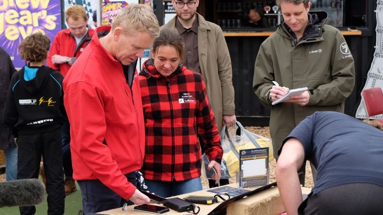 Labour leader Chris Hipkins buys an item from the SunSaver stall at the Summit to Sea: 4x4, Camp & Outdoor Show while on the campaign trail in Upper Hutt. Image source: Mandy Te
