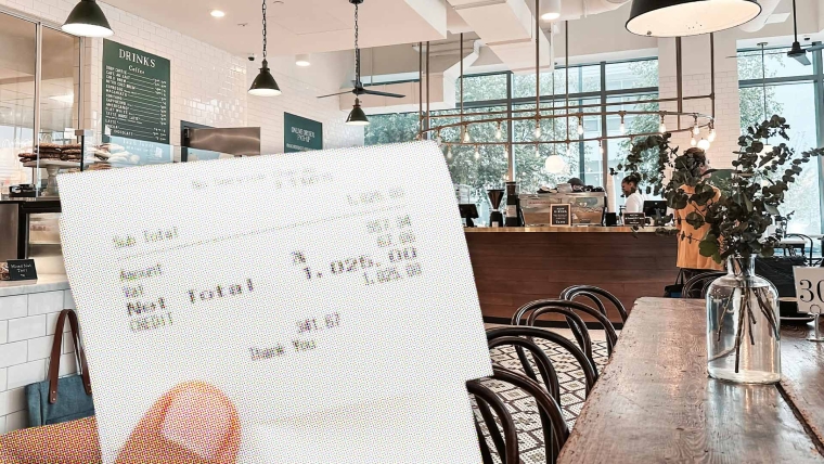 A composite image of a restaurant with tables and chairs overlayed with a hand holding a receipt.