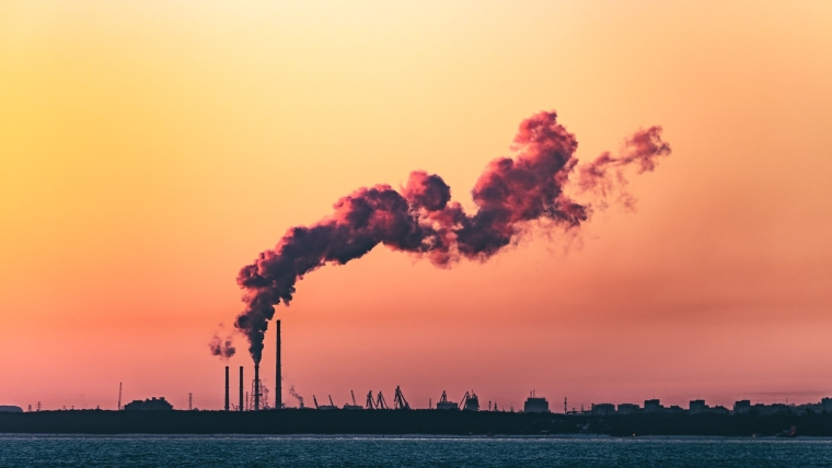 Image of smokestacks against a sunset. 