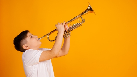 Boy blows trumpet