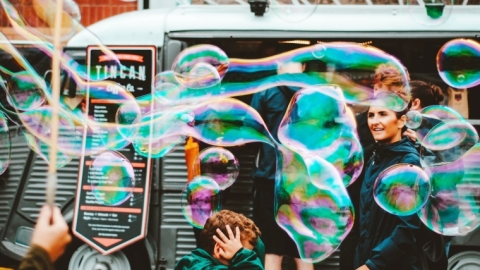 Boy covers his head to avoid a barrage of bubbles