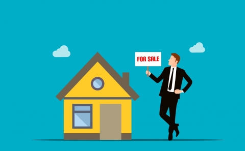Image of real estate agent with For Sale sign