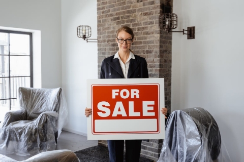 Real estate agent holding for sale sign