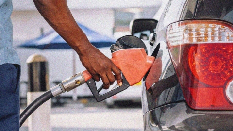 A close up of a person's hand, as they refuel their vehicle at a petrol station.