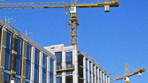 Crane and building under construction against blue sky.